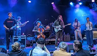 Tapir! play music on a stage in front of a crowd, lit by blue lights.