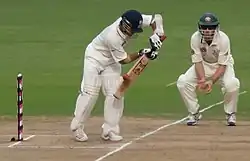 Sachin Tendulkar wearing pads to protect his legs. Both he and the short leg fielder wear cricket helmets for protection.