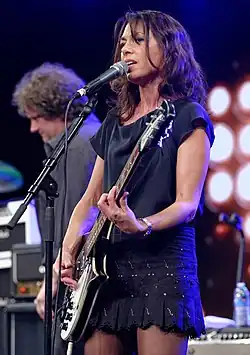A woman playing a black and white electric guitar