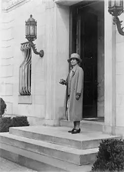 Coolidge standing on the steps of Dupont Circle wearing a coat and hat