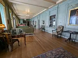 A long, narrow room displaying a range of oil painting, ceramics and antique furniture