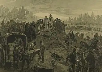A vicar stands at an open grave, which is being filled with a coffin. Several others are being unloaded from a covered waggon. Crowds of people are shown paying their respects.