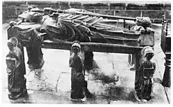 View of the flagstone depicting Saint Ronan. Note how the end of his cross has been pushed into the mouth of the lion resting at his feet, its paws placed on a blazon. A reclining angel is placed by Ronan's head.