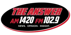 A black oval with red trim with three lines of text. The first line is "THE ANSWER" in italiczed red text with a white trim. The second line is "AM 1420 FM 102.9", with "AM" and "FM" in red and "1420" and "102.9" in white. The bottom line is "NEWS. OPINION. INSIGHT." in a smaller white text.