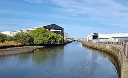 Photo of stream surrounded by industrial buildings.