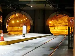 Two large tunnel tubes with rails embedded in concrete running into them