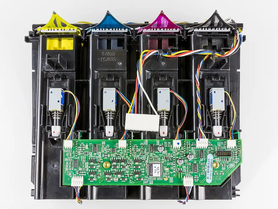 yellow blue magenta and black ink blocks are pressed against bent aluminum triangles covered in melted wax of each color. a black PC/ABS plastic frame holds everything together.
