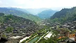 A town with traditional houses on the slopes of both sides of a small stream