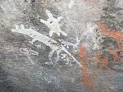 gray stone wall with white and orange primitive drawings