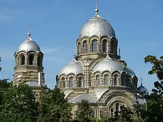 The church of the Theotokos Orans (Our Lady of the Sign) in Vilnius demonstrates typical features of developed Byzantine revival: exposed two-tone, striped, masonry; four symmetrical apses tightly fused into the main dome, creating a tall triangular outline; arcades blending into the domes; and a relatively small belltower, clearly subordinate to the main dome.
