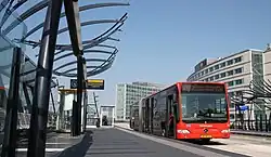 Red articulated bus at a station